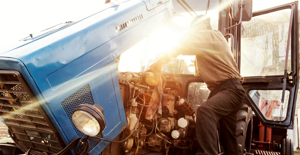 Une loupe examine un moteur de tracteur, symbolisant l'importance du diagnostic technique.